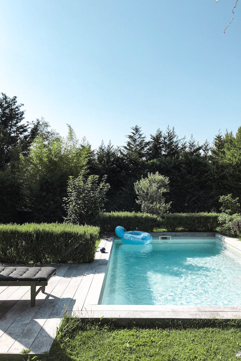 pexels-photo-2876789-2876789 Quiet backyard pool surrounded by greenery and blue skies, ideal for relaxation.